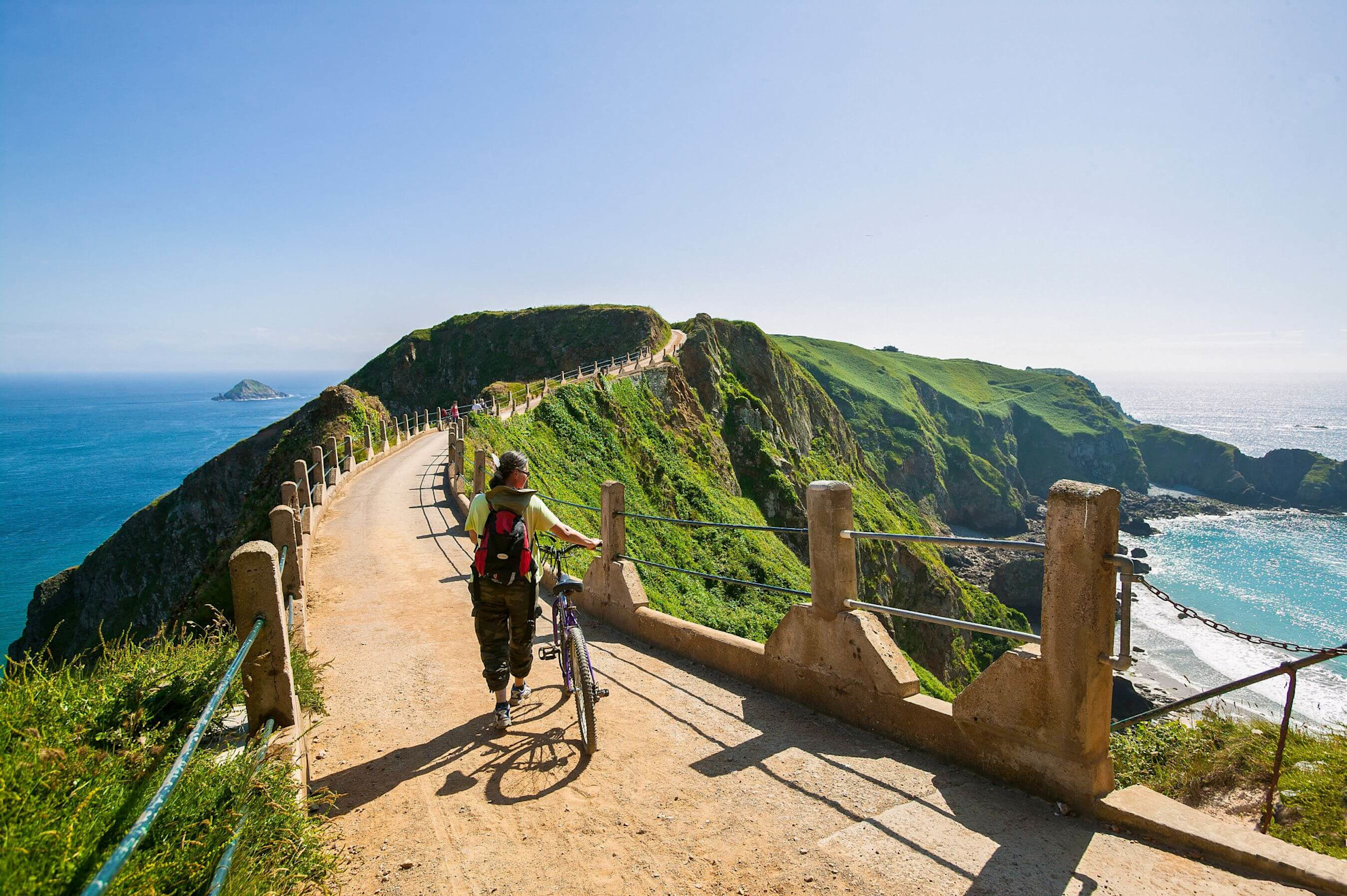 Woman with bicycle on the coastpath on the island of Sark, Channel Islands
